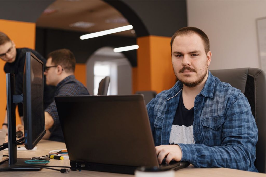 Una hombre escribiendo en una computadora portátil, desarrollador de software.