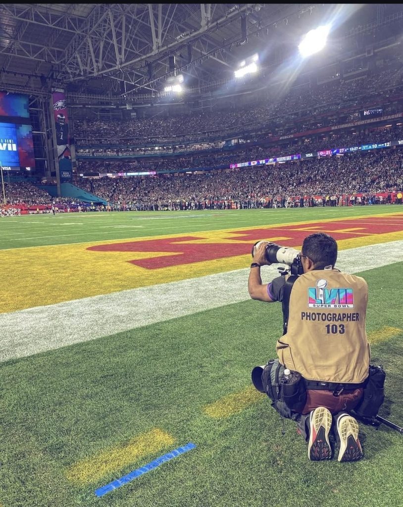 Un fotógrafo a la orilla de un estadio de fútbol americano capta imágenes de un partido.