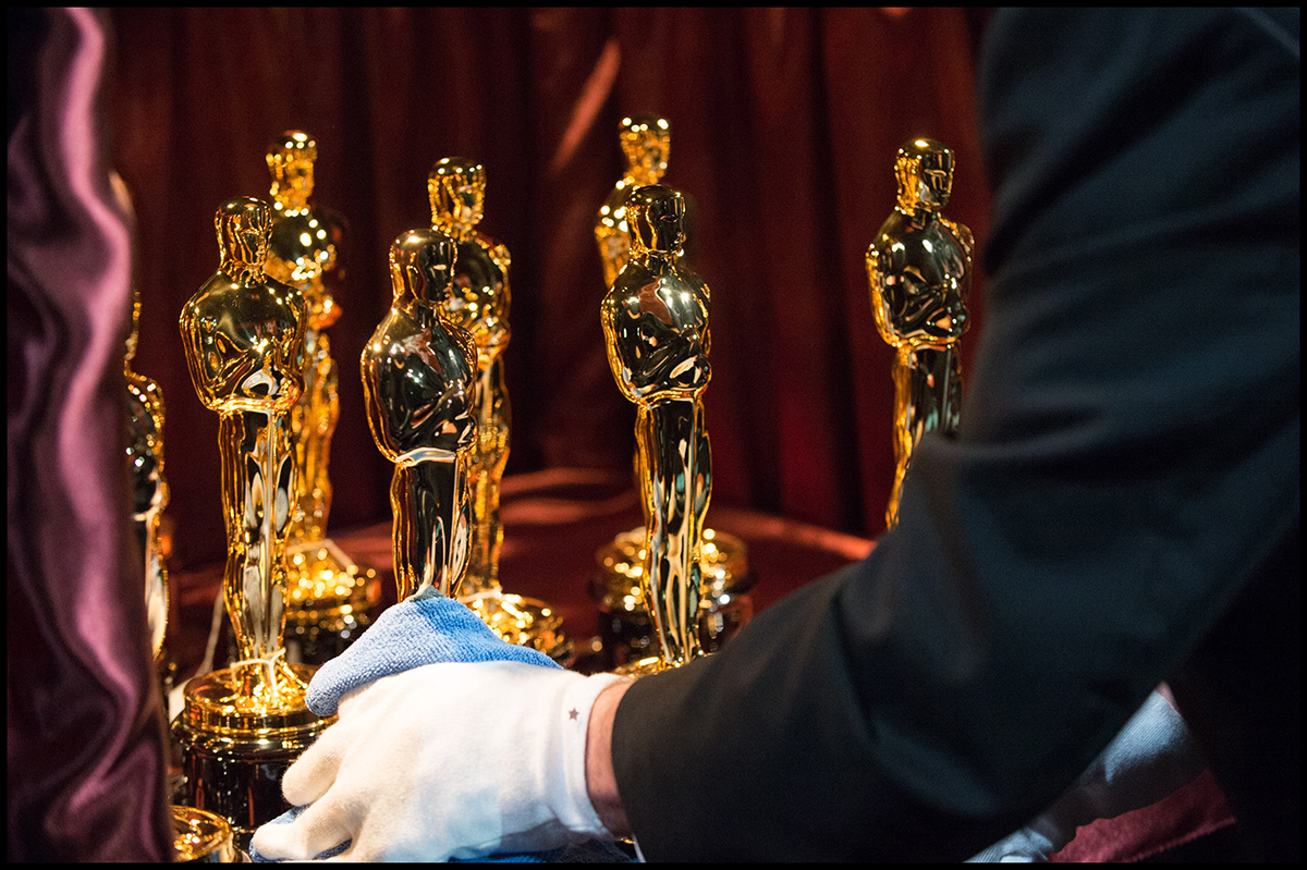 La estatuilla dorada de los Premios Oscar colocada por una mano con guante blanco