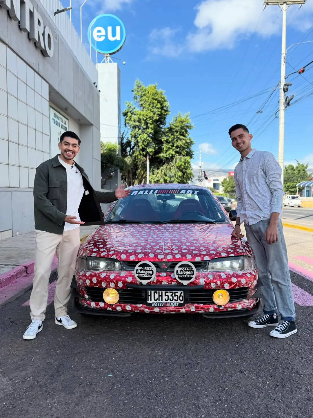 Joven dueño del carroenvuelto en papel de regalo.
