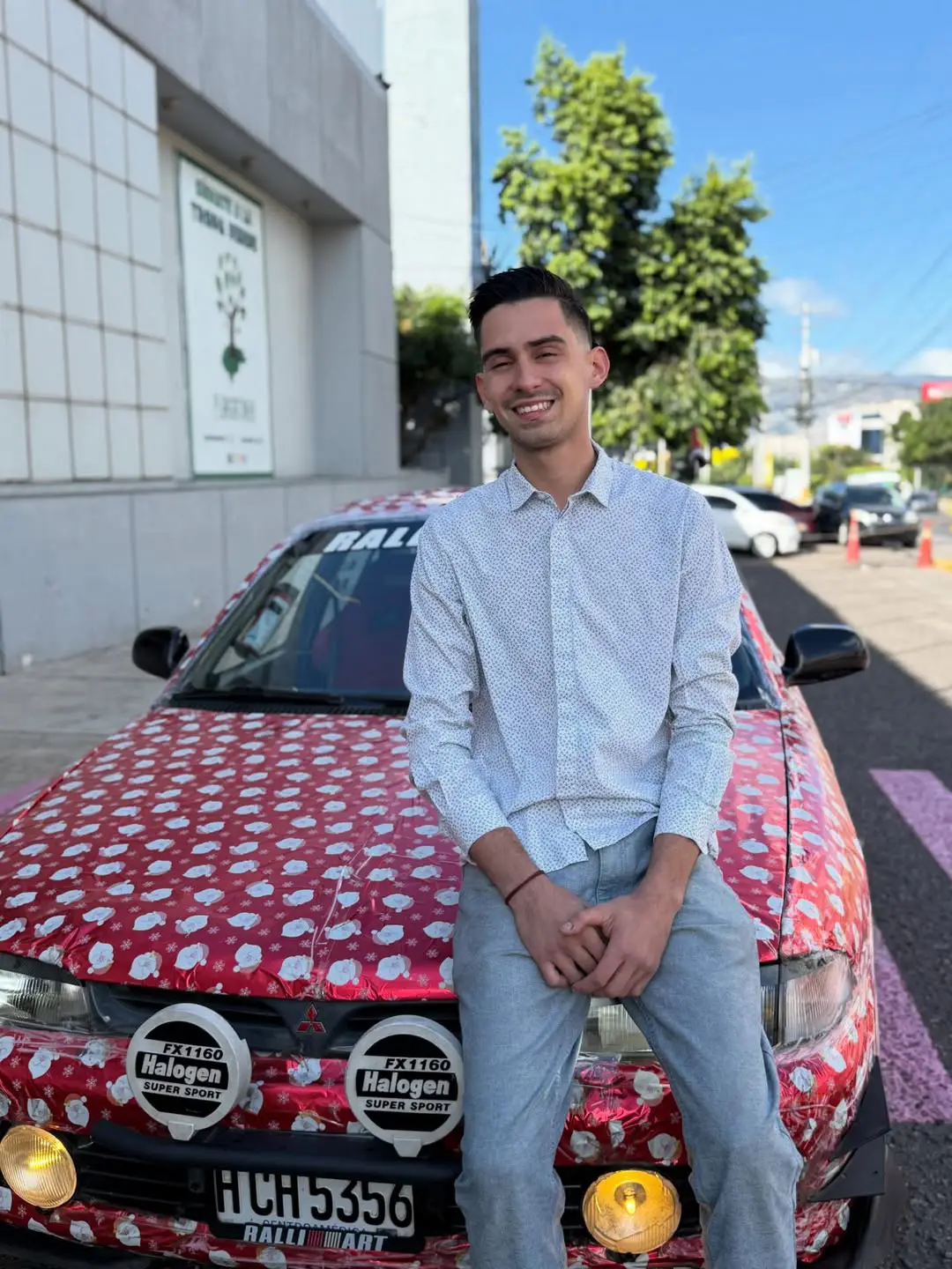 Joven dueño del carroenvuelto en papel de regalo.