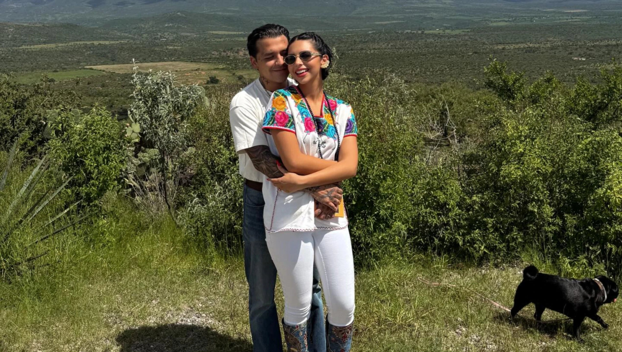 Imagen de Christian Nodal y Ángela Aguilar abrazados en la cima de una montaña. 