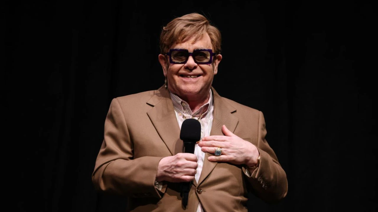 Elton John con lentes y un traje de color café. Foto: cortesía de Internet 