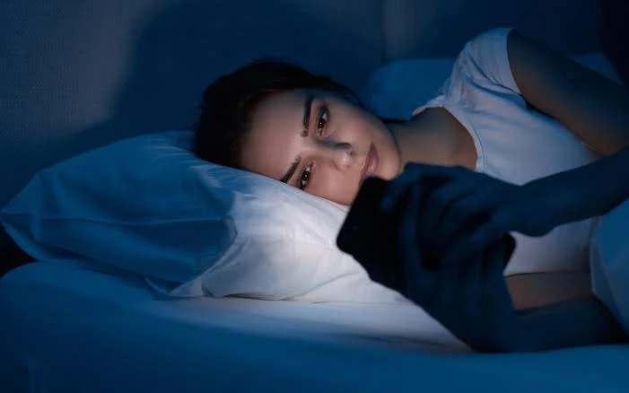 Mujer sin poder dormir por estar con celular