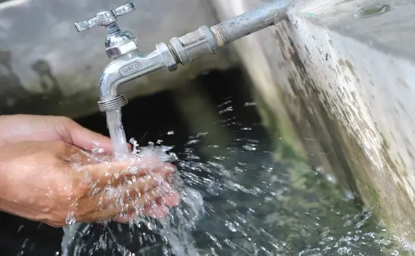 Grifo abierto llenando una pila con agua.
